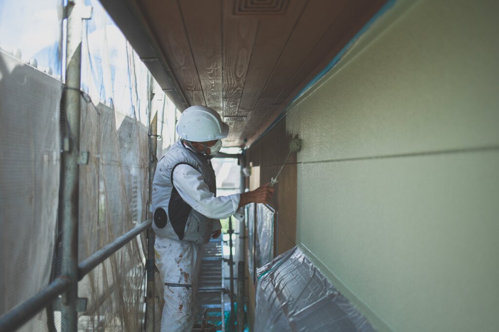 足場で外壁を塗装する作業員